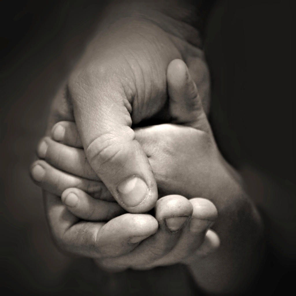 A small hand held in an adult hand