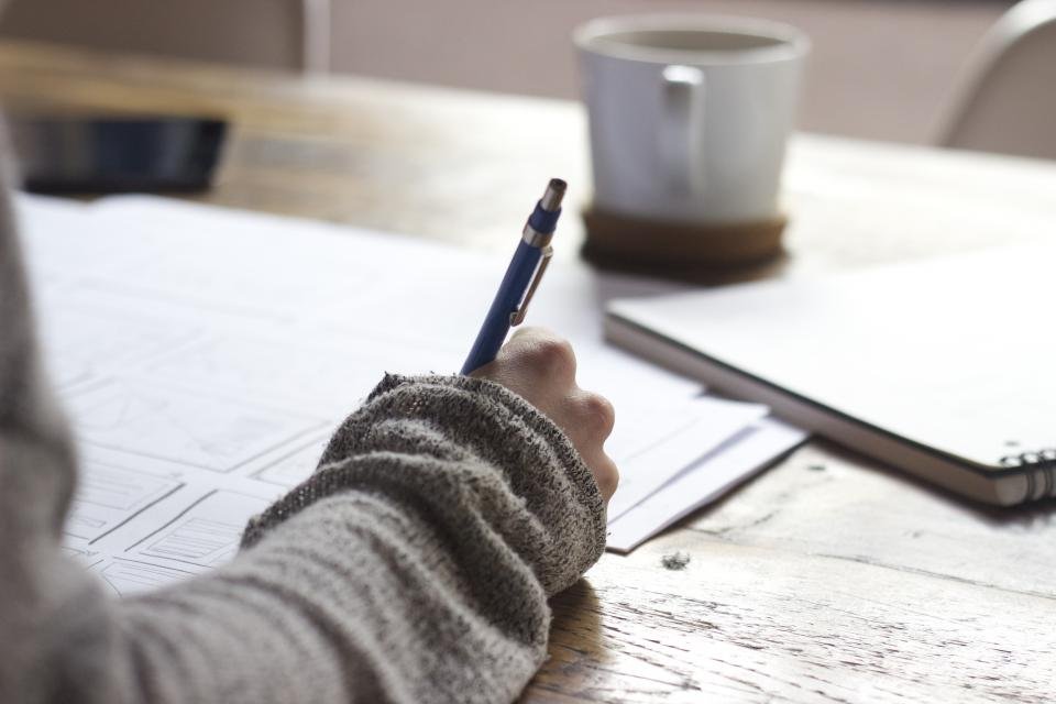 Writing in a notebook with coffee alongside